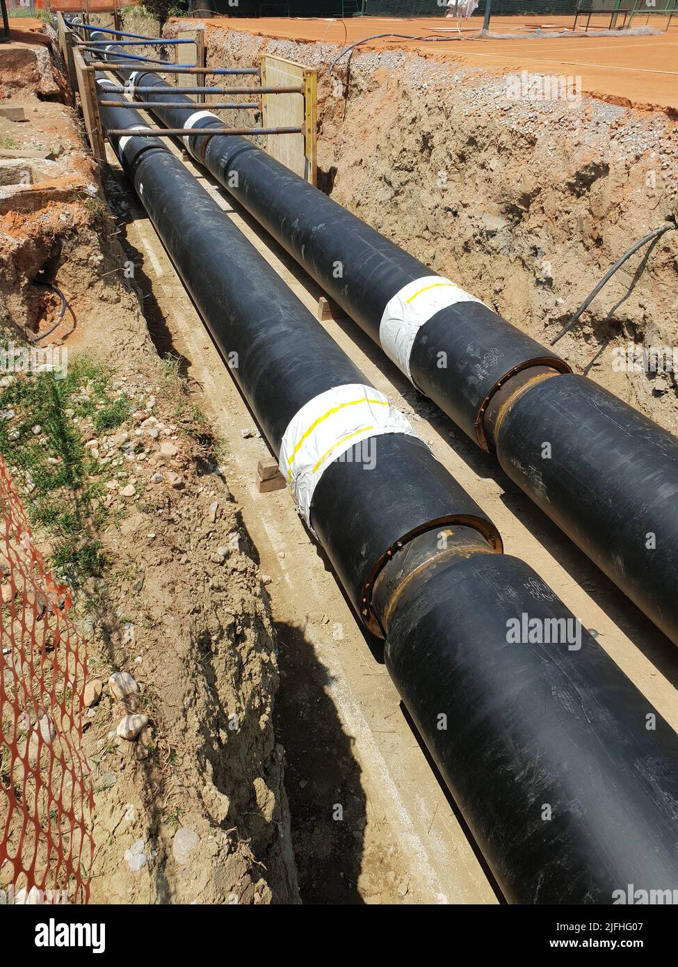 Reconstruction site of district heating system pipeline and replacement of old pipes with new ones. Laying heating pipes in a trench at construction s Stock Photo