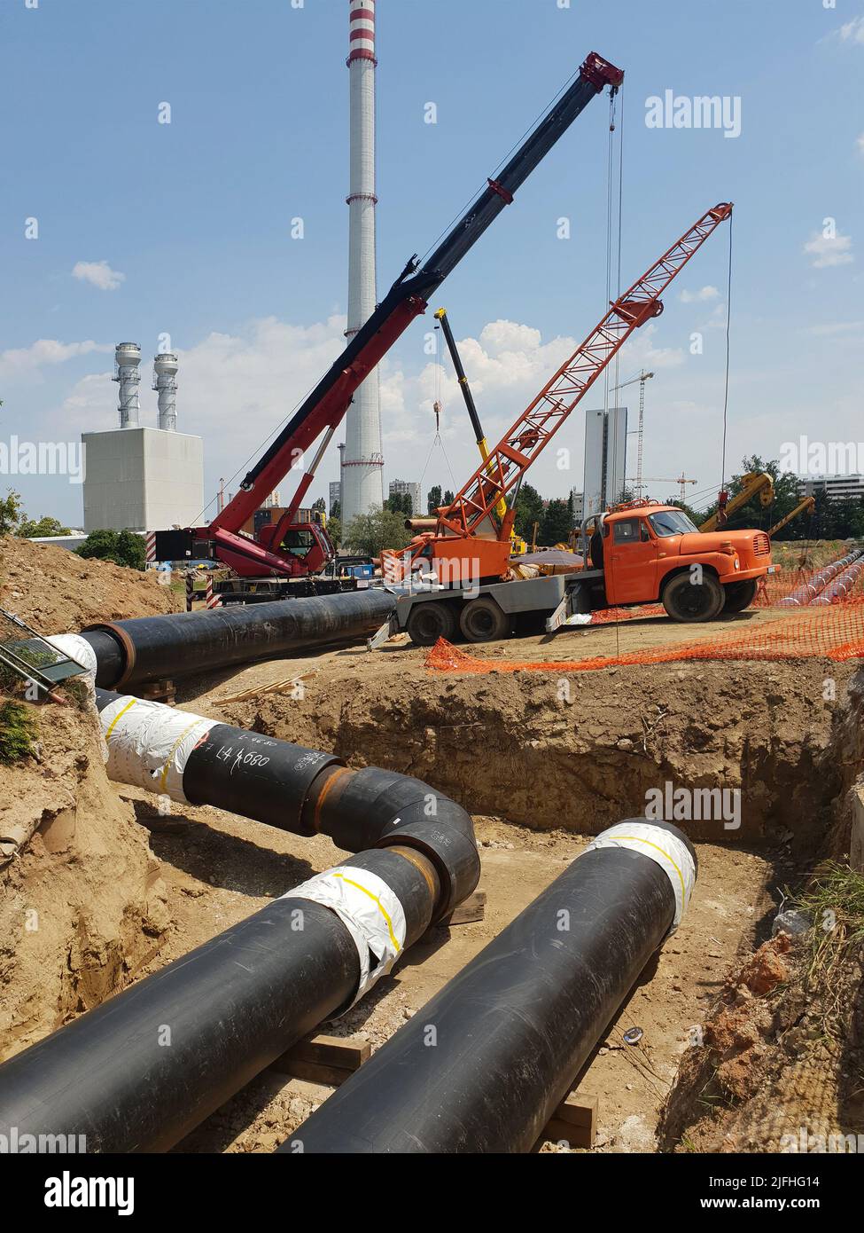 Reconstruction site of district heating system pipeline and replacement of old pipes with new ones. Laying heating pipes in a trench at construction s Stock Photo