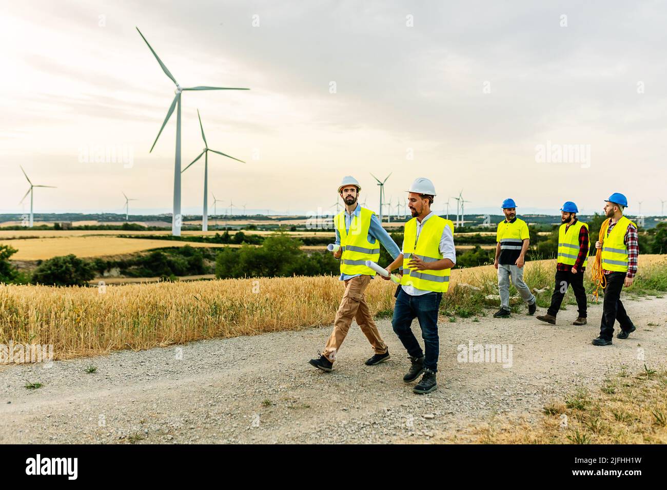 Technicians and engineers walking on a field path at a wind farm Stock Photo