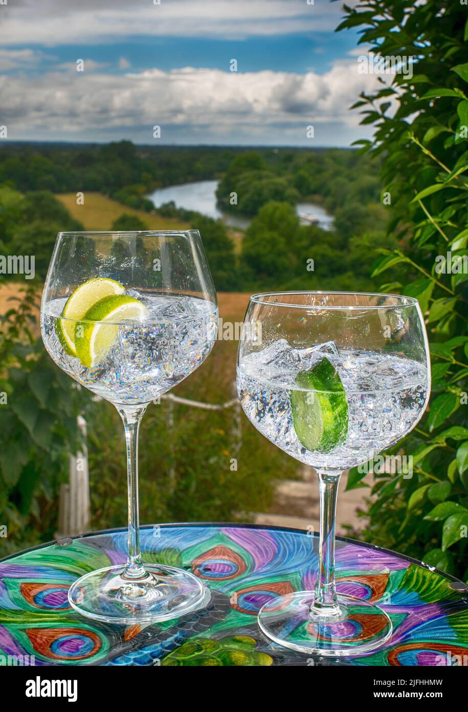 Two gin glasses, large and small, with ice cubes and slice of lime