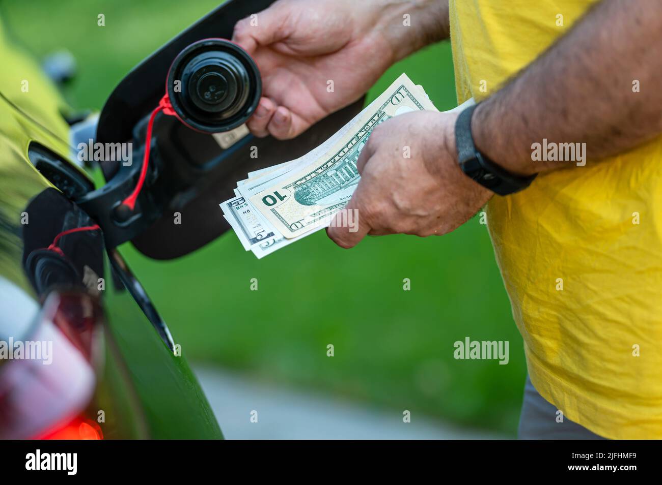 hand of man that puts money into the tank of car, closeup, concept of