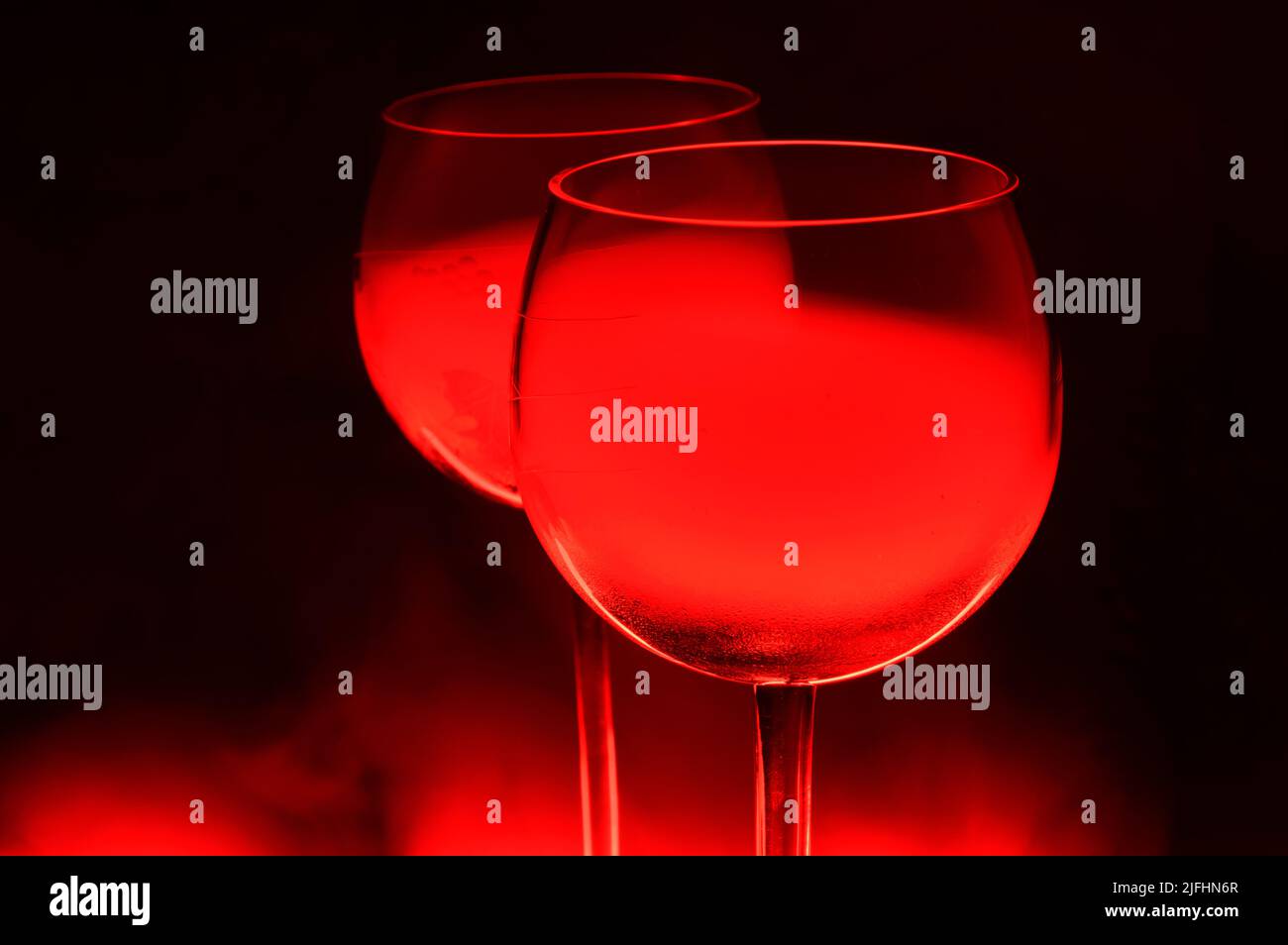 Two Glasses of a Red Alcoholic Cocktail on Dark Background with smoke and backlight. Very dangerous fire cocktail - close up photo. Background picture Stock Photo