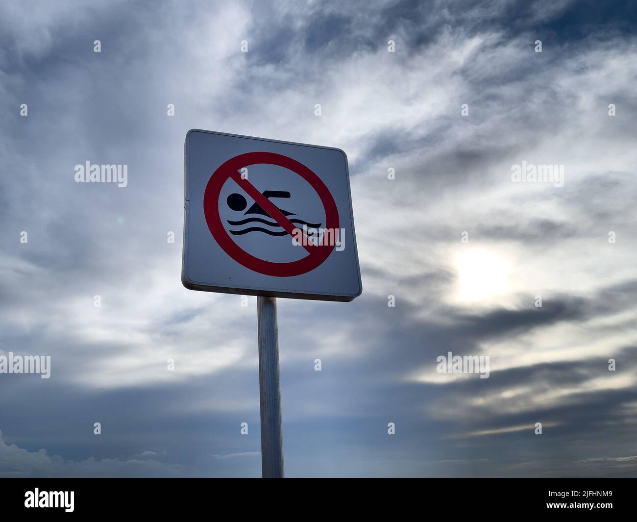 No swimming warning sign with blue sky Stock Photo