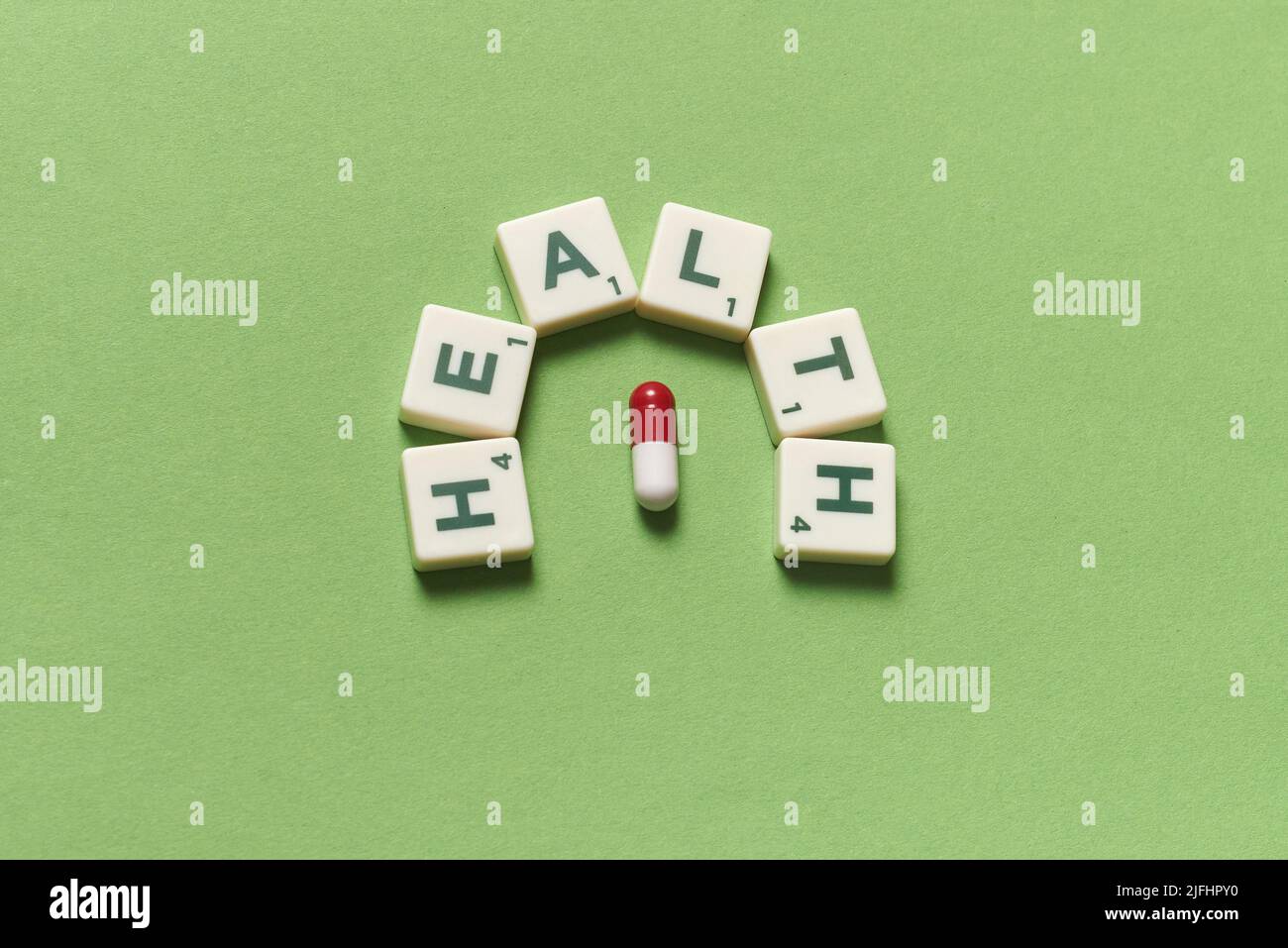Health word formed of scrabble blocks and pharmaceutical pill over