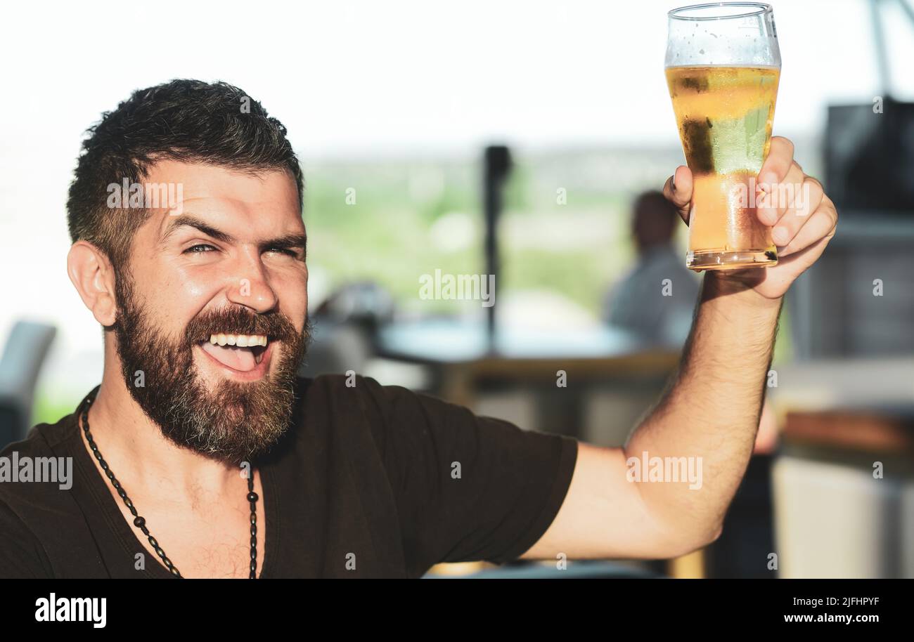 Handsome barman holding a pint of beer. Man holds glass of beer. Enjoy in pub. Beer time Stock Photo