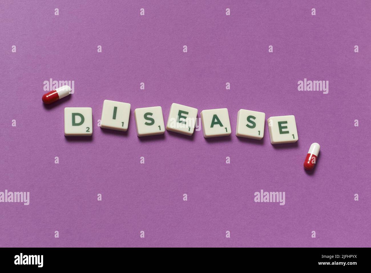 Disease word formed of scrabble blocks and pharmaceutical pills over