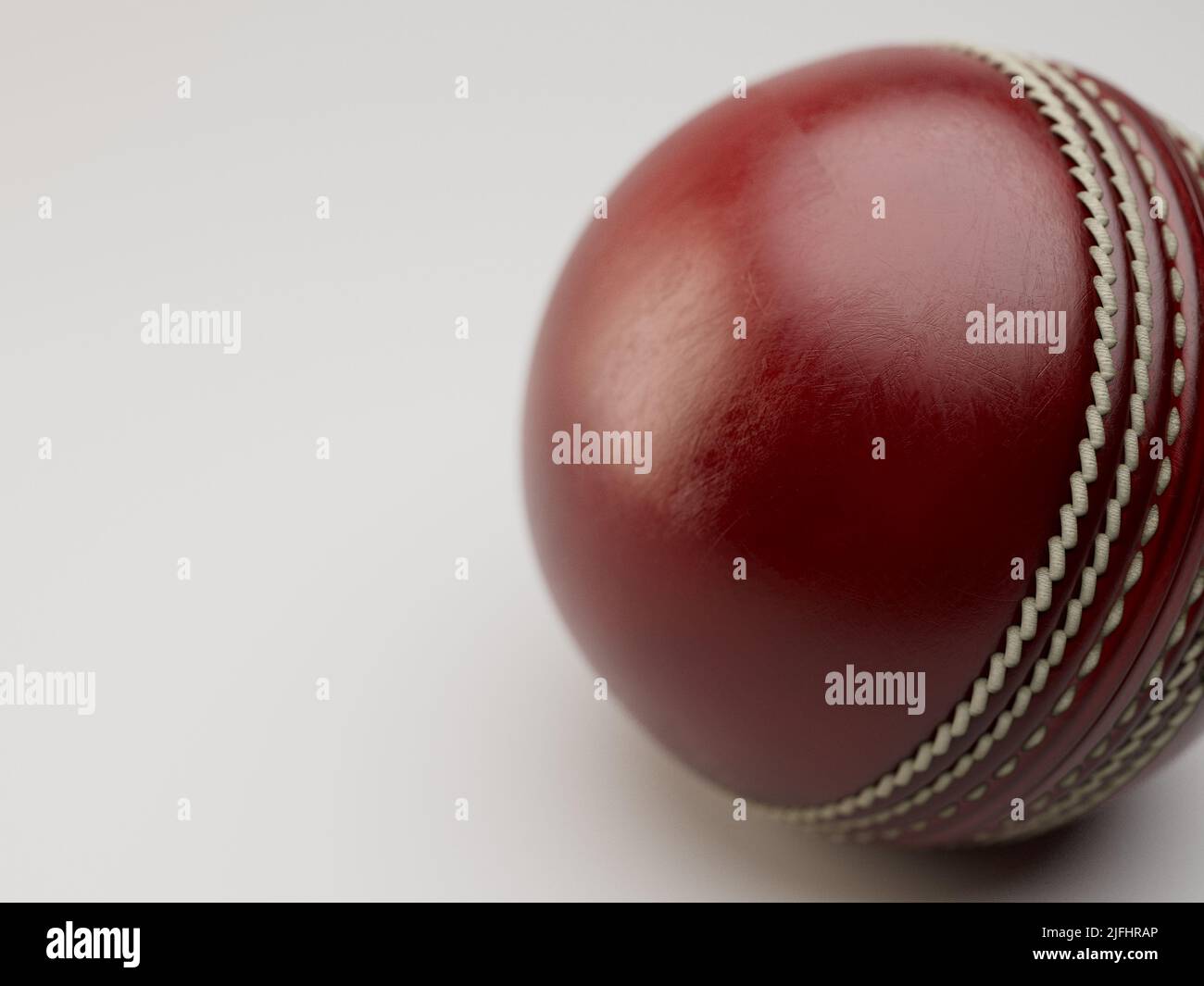 A regular red cricket ball with white stitching on an isolated