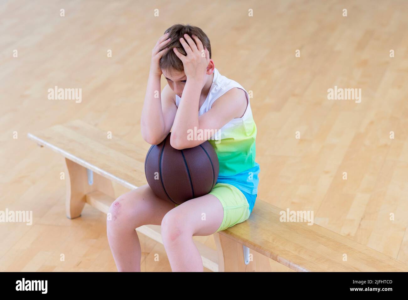 Sad disappointed boy with basketball ball in a physical education lesson Stock Photo