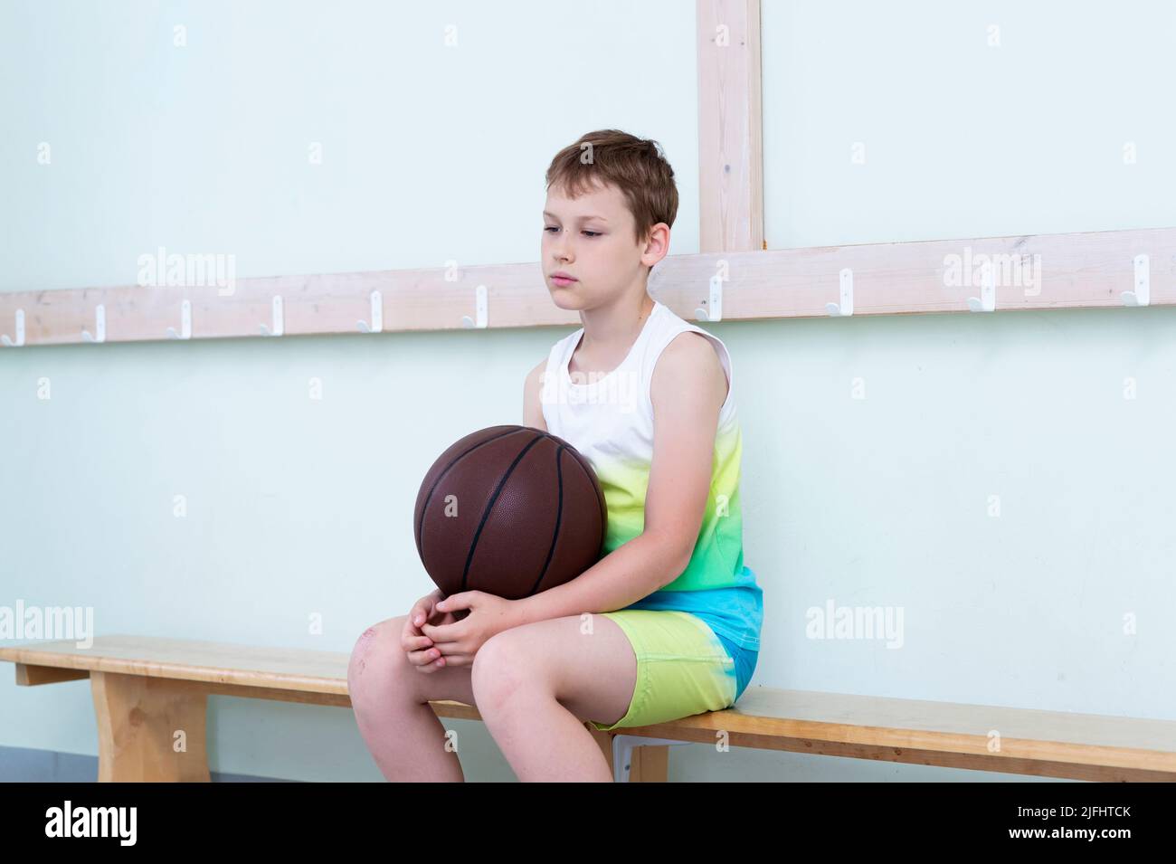 Sad disappointed boy with basketball ball in a physical education lesson Stock Photo