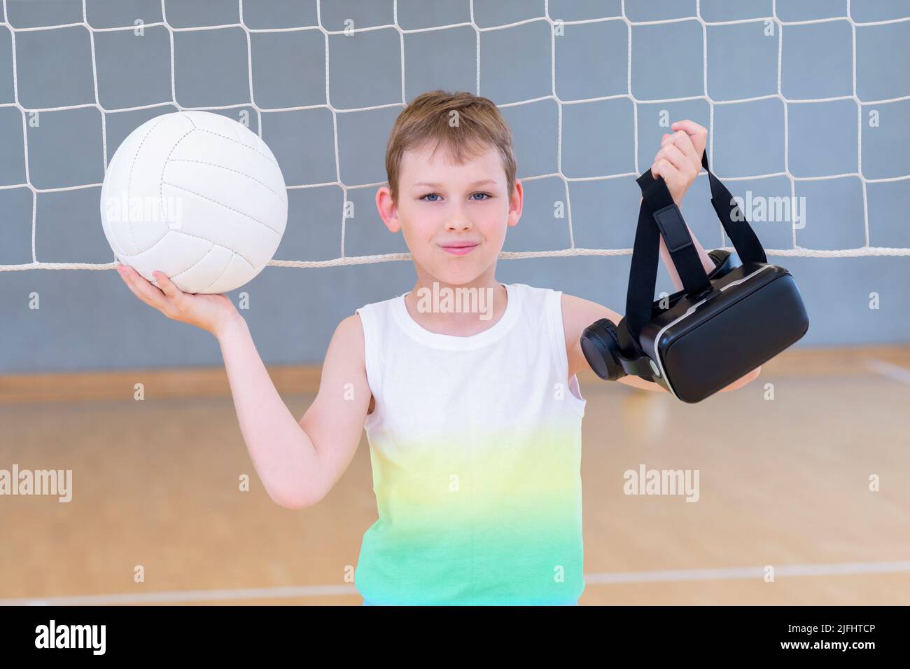 School kid with interactive glasses playing volleyball in a physical education lesson. Horizontal interactive sport theme poster, greeting cards, head Stock Photo
