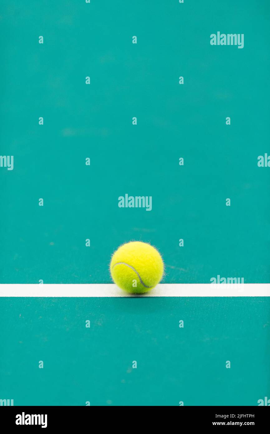 Yellow tennis ball with white line on mint court. Vertical sport theme poster, greeting cards Stock Photo