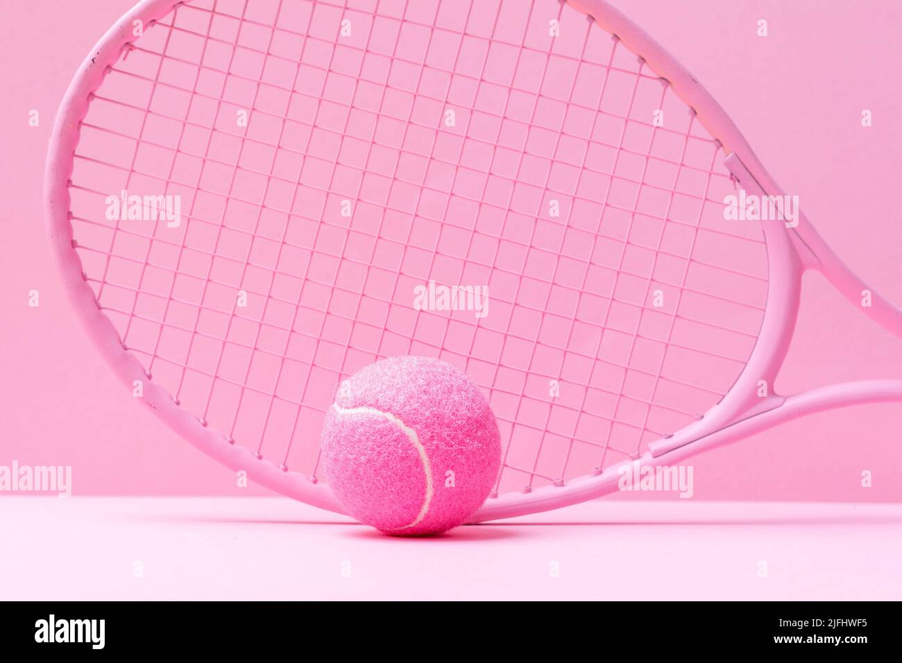 Pink tennis racket and pink ball on pink background. Horizontal sport theme poster, greeting cards, headers, website and app Stock Photo