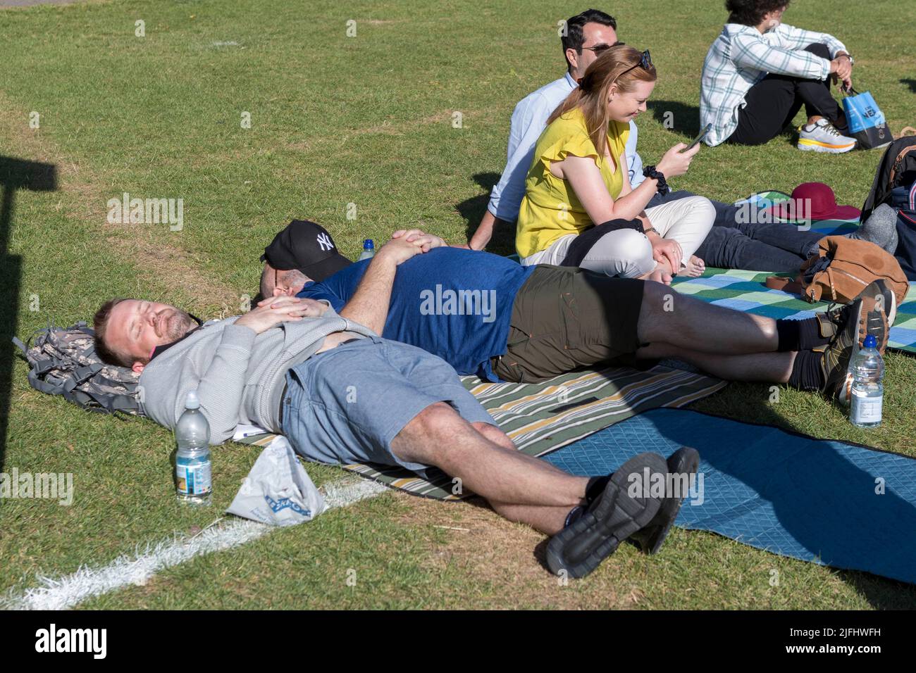 Tennis fans form long queues at Wimbledon Park this morning for tickets ahead of The Championship.   Pictured: fans sunbathe while waiting in the queu Stock Photo