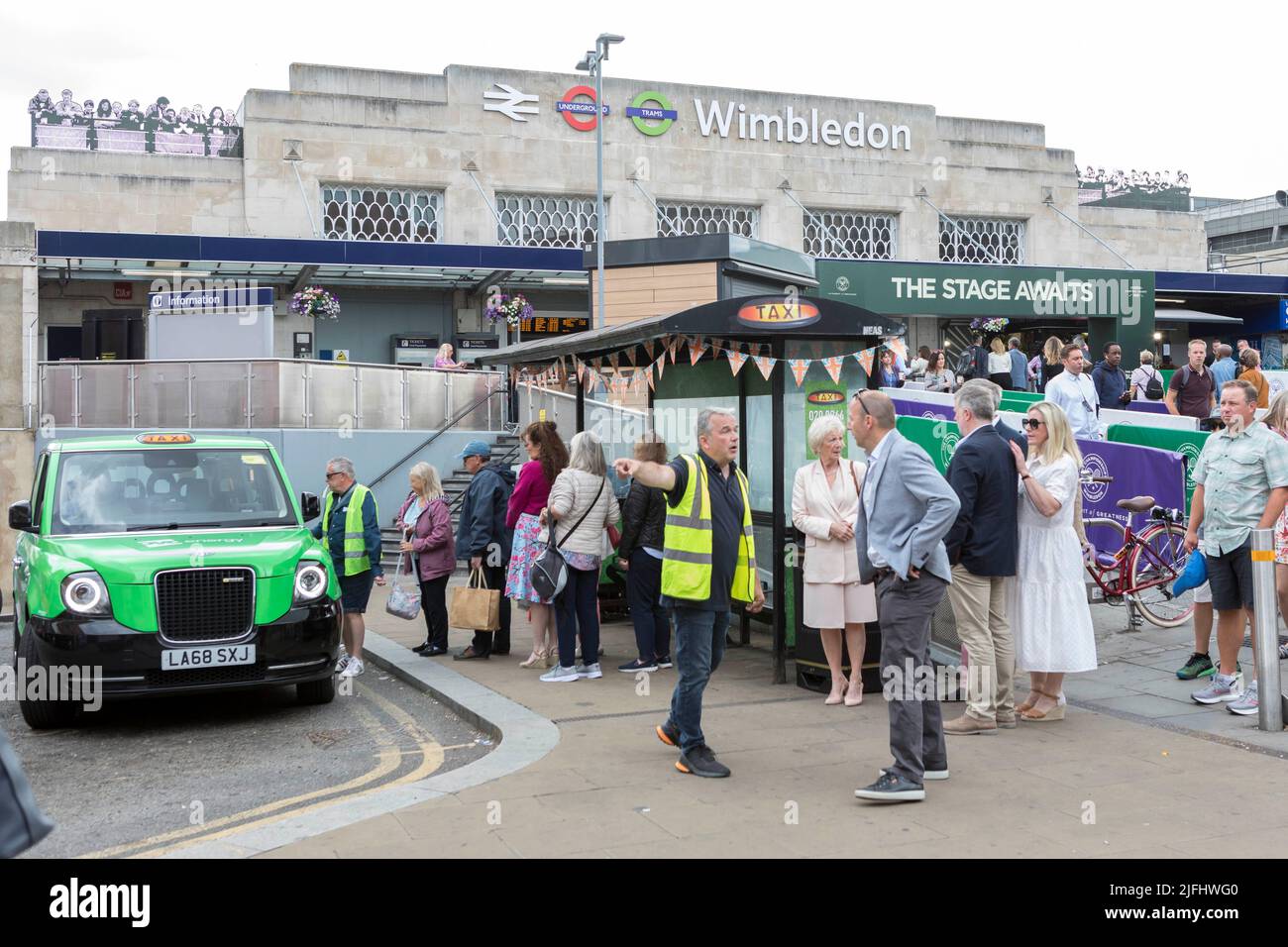 Tennis fans ushered into shared taxis outside Wimbledon train station ahead of the 2022 Championship.   Image shot on 27th June 2022.  © Belinda Jiao Stock Photo