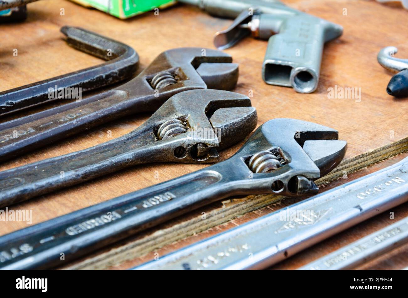 A collection of adjustable spanners on a wooden table top. Stock Photo