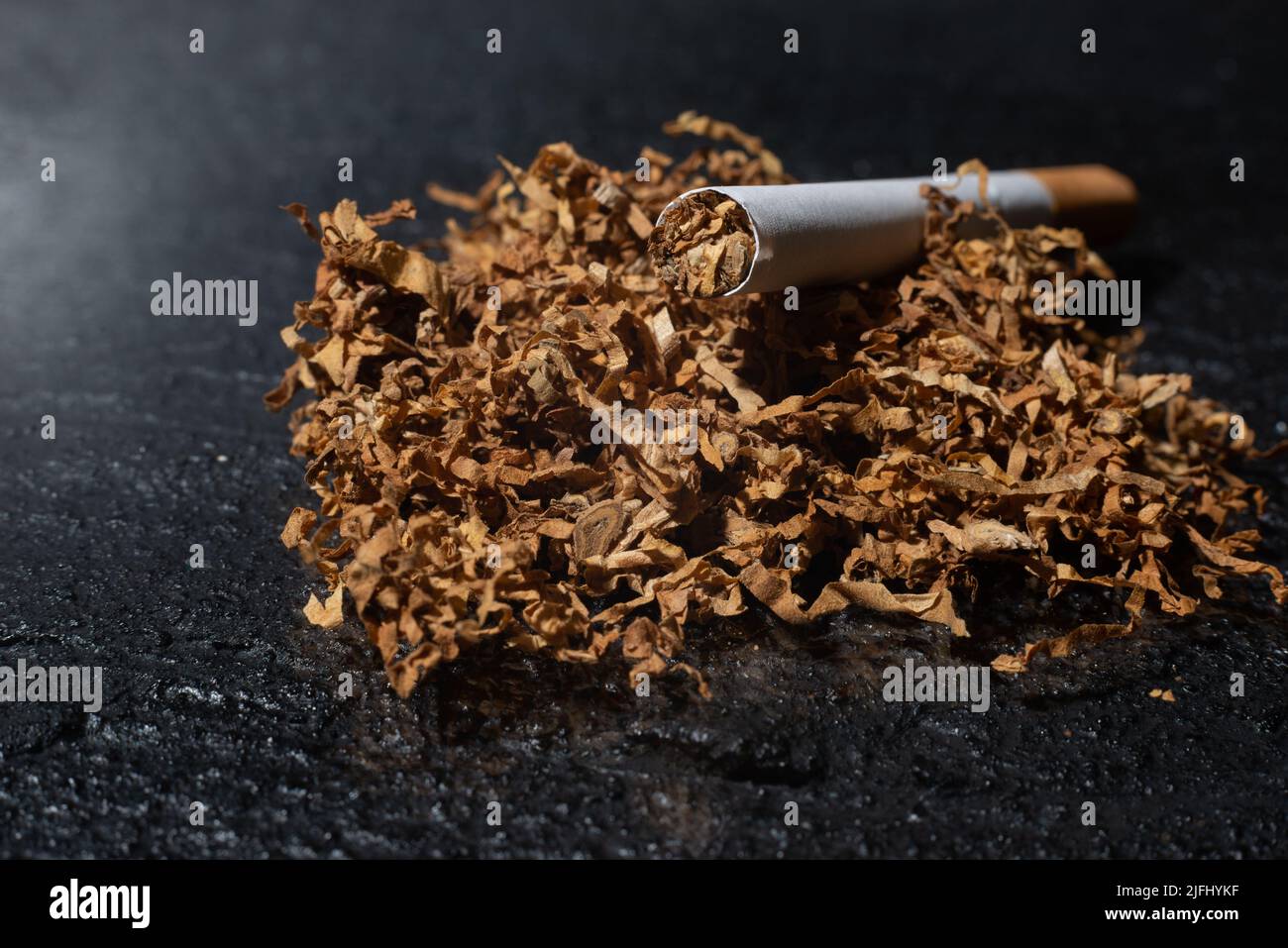 Cigarette and smoking tobacco leaves on a dark background. Bad habits