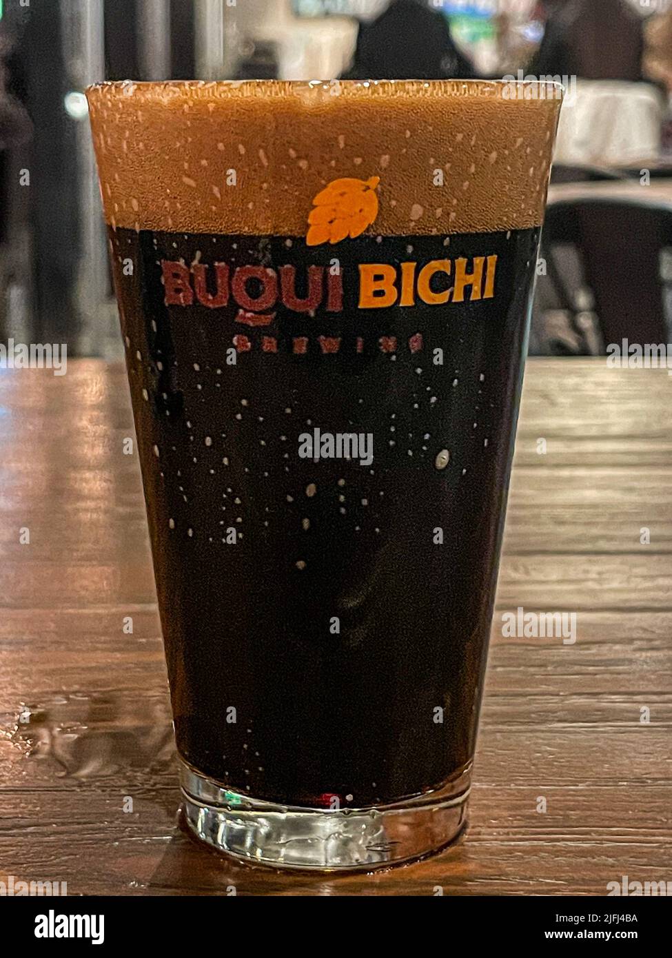 Glass glass with dark, brown Buqui Bichi craft beer on a wooden table