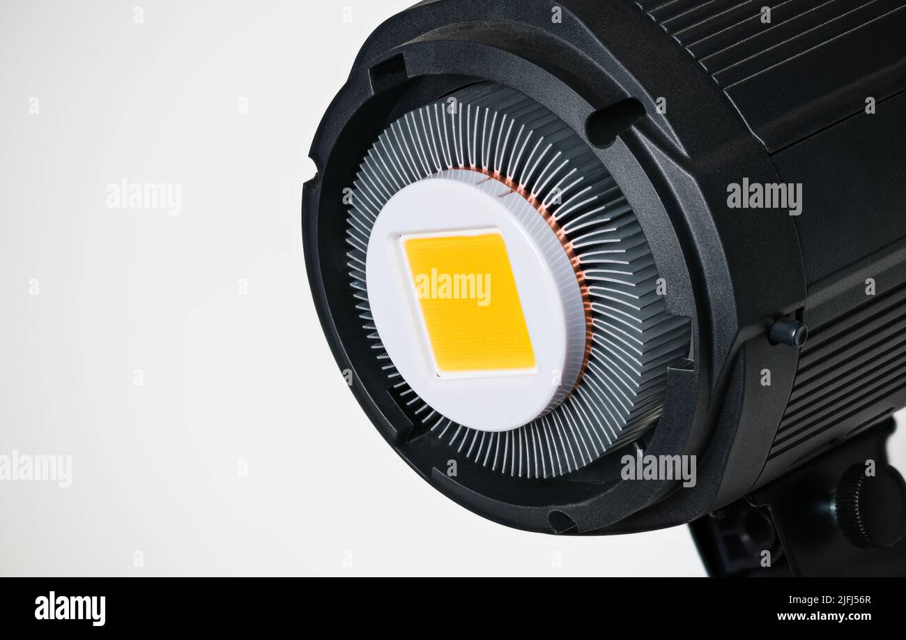 Yellow LED module in photographic reflector with aluminum cooling fins on white background. Black high-power electric light from semiconductor diodes. Stock Photo