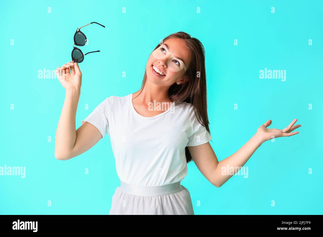 Happy young woman with sun tanned skin and sunglasses on blue