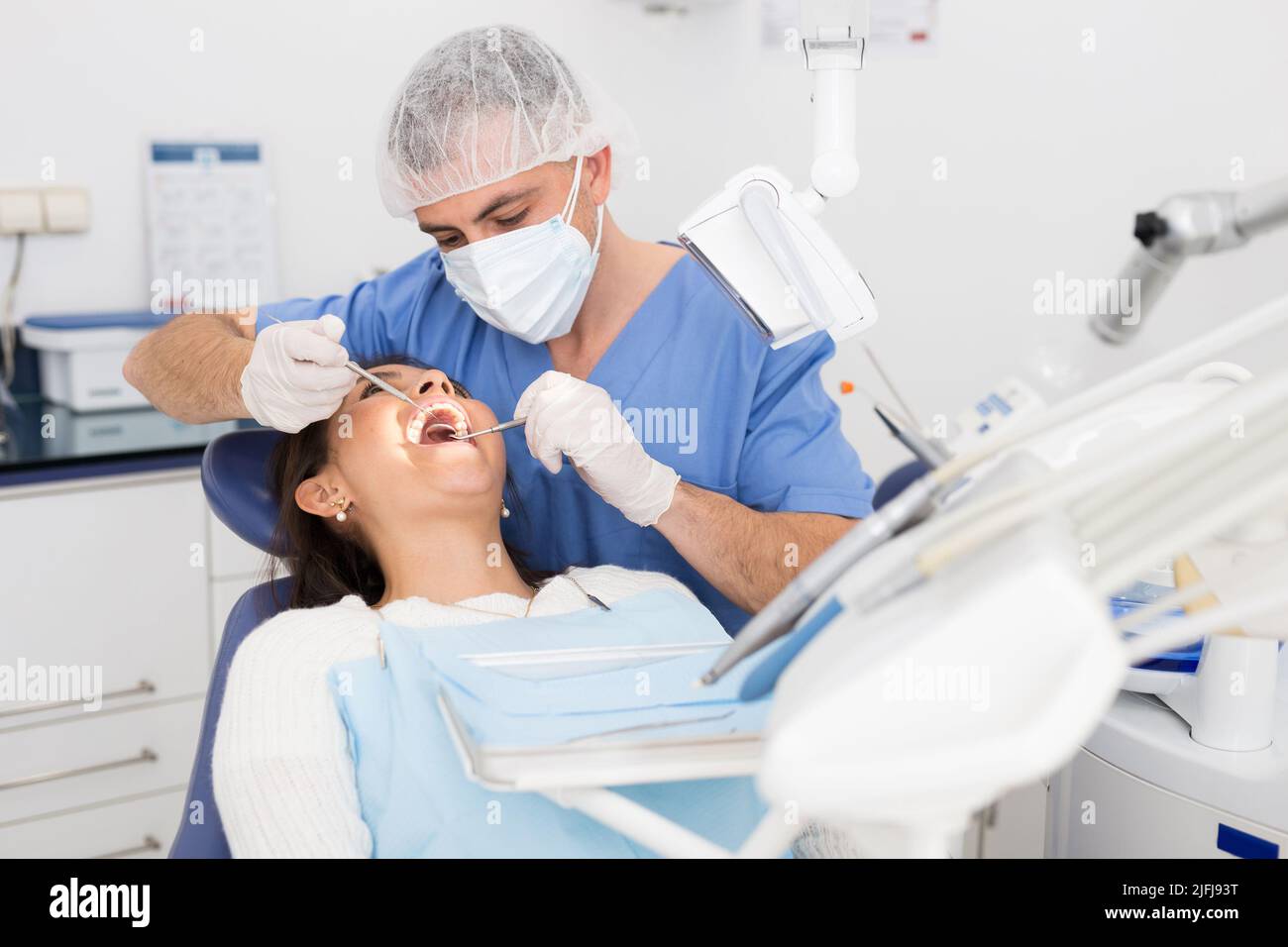 Dentist man examining a latin female patient teeth Stock Photo Alamy