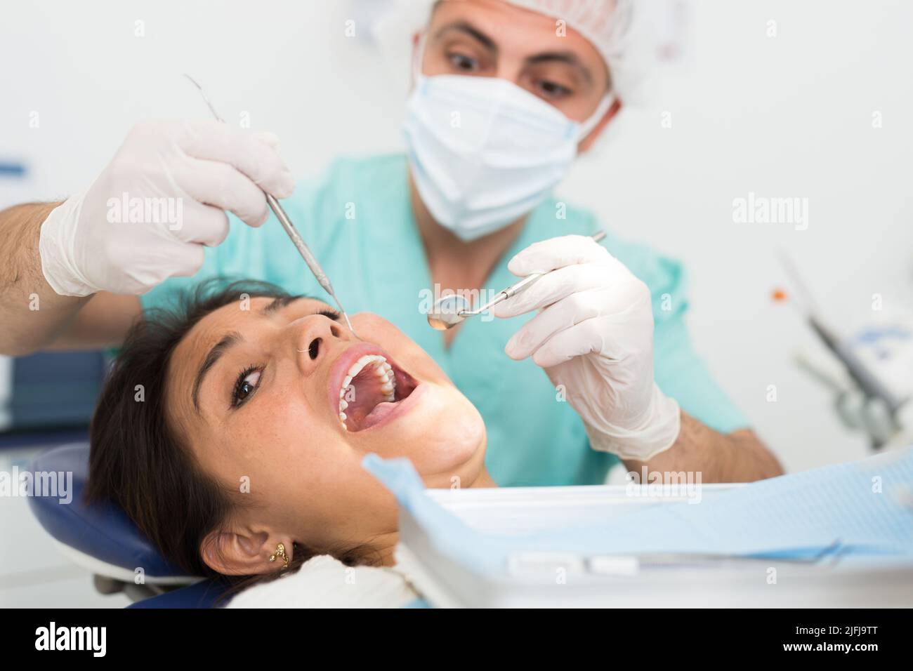 Dentist man examining a latin female patient teeth Stock Photo Alamy