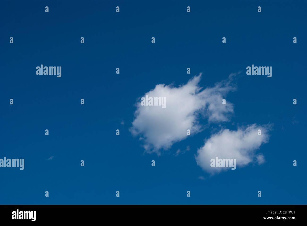 The horizontal photo is a blue sky with white fluffy clouds. Background, screensaver. Summer. Cloudy. Sunshine - Stock Image
