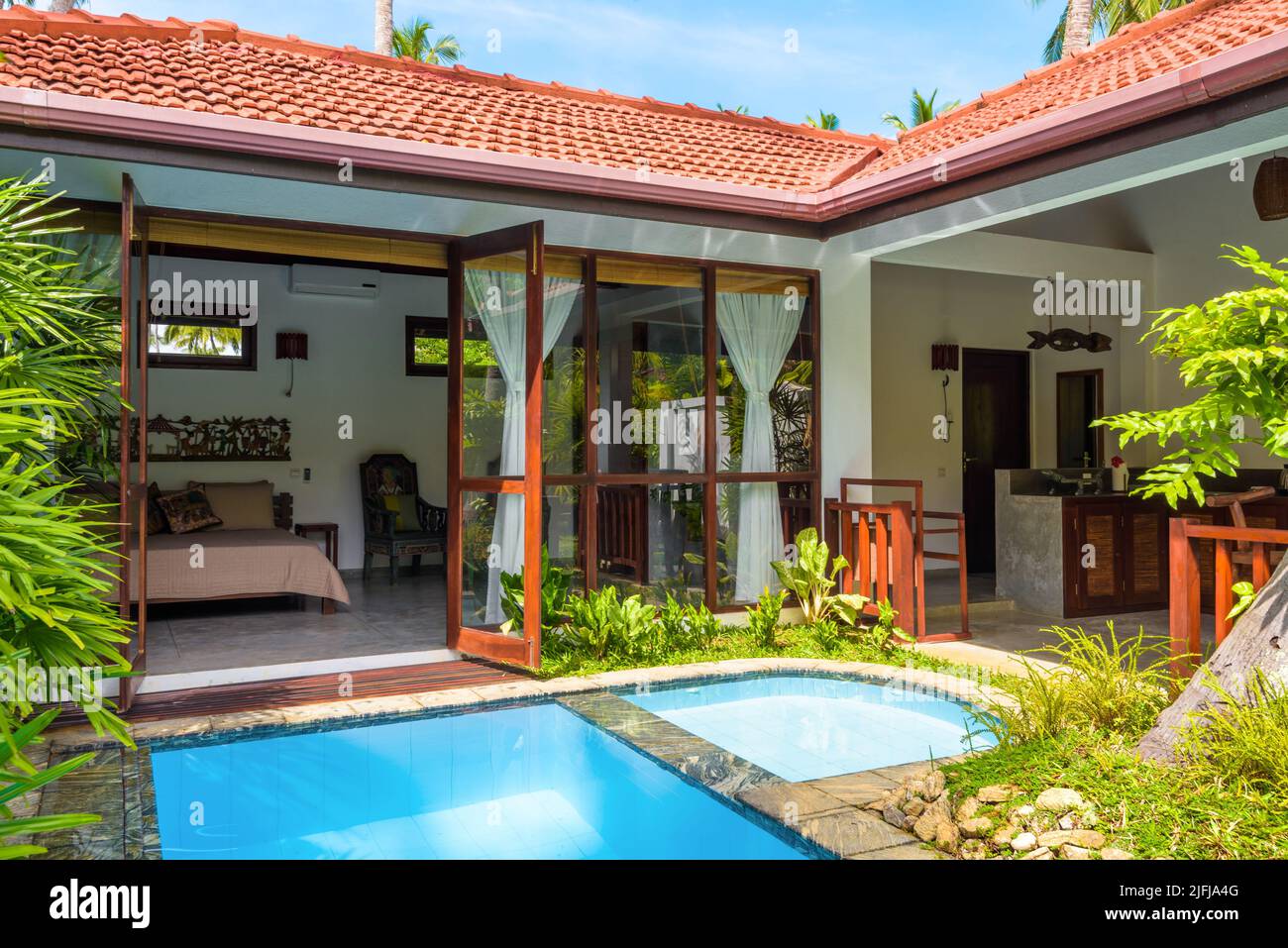Sri Lanka - Nov 4, 2017: Luxury home with pool in backyard. Summer vacation house in Indian or Caribbean style and garden in courtyard. Nice villa on Stock Photo
