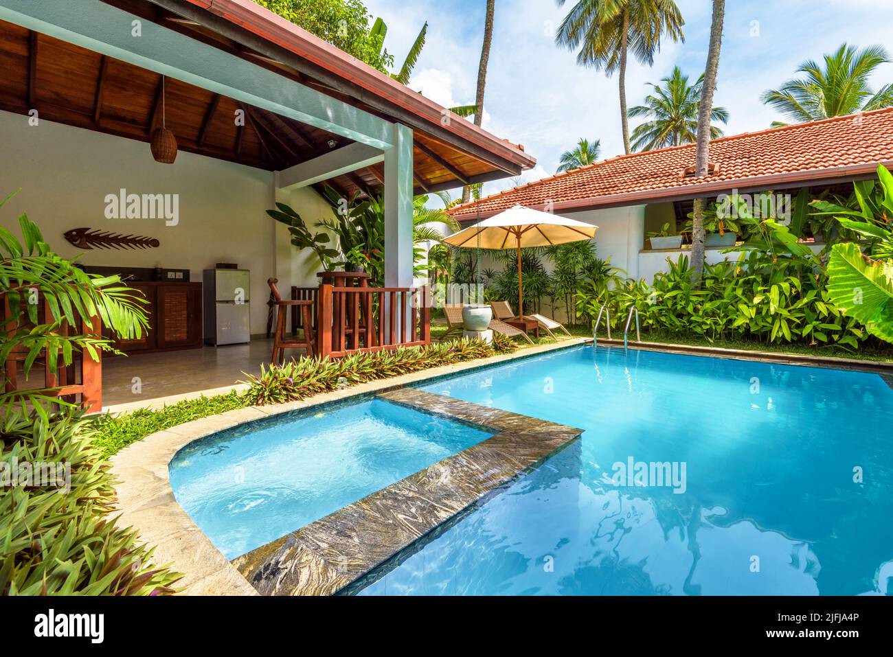 Sri Lanka - Nov 4, 2017: Luxury home with pool and terrace in backyard. Bungalow in Indian or Caribbean style and garden in courtyard. Nice villa on t Stock Photo