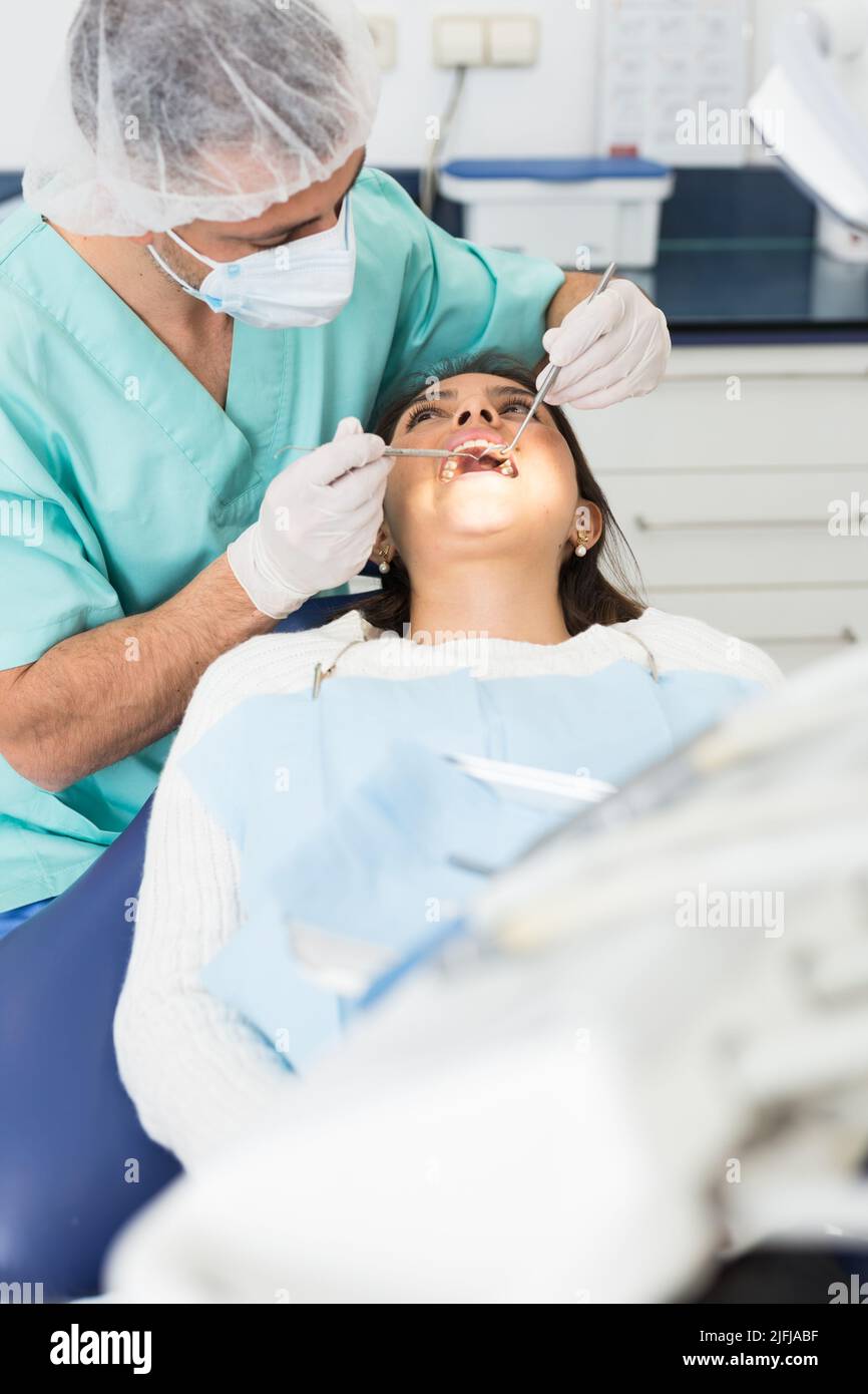 Dentist man examining a latin female patient teeth Stock Photo Alamy