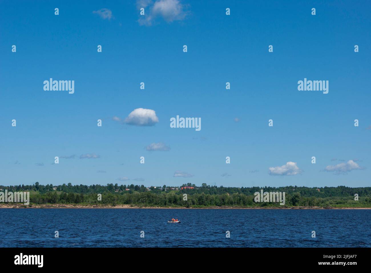 Deep cold ryokana in the north of Russia. The seasons are summer. A sandy beach with green bushes growing on it. White clouds in the blue sky - Stock Image