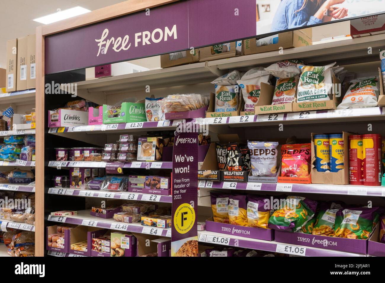 A gluten free aisle with gluten free products on shelves with a 'Free From' advertising board at a Tesco supermarket in Basingstoke, UK Stock Photo