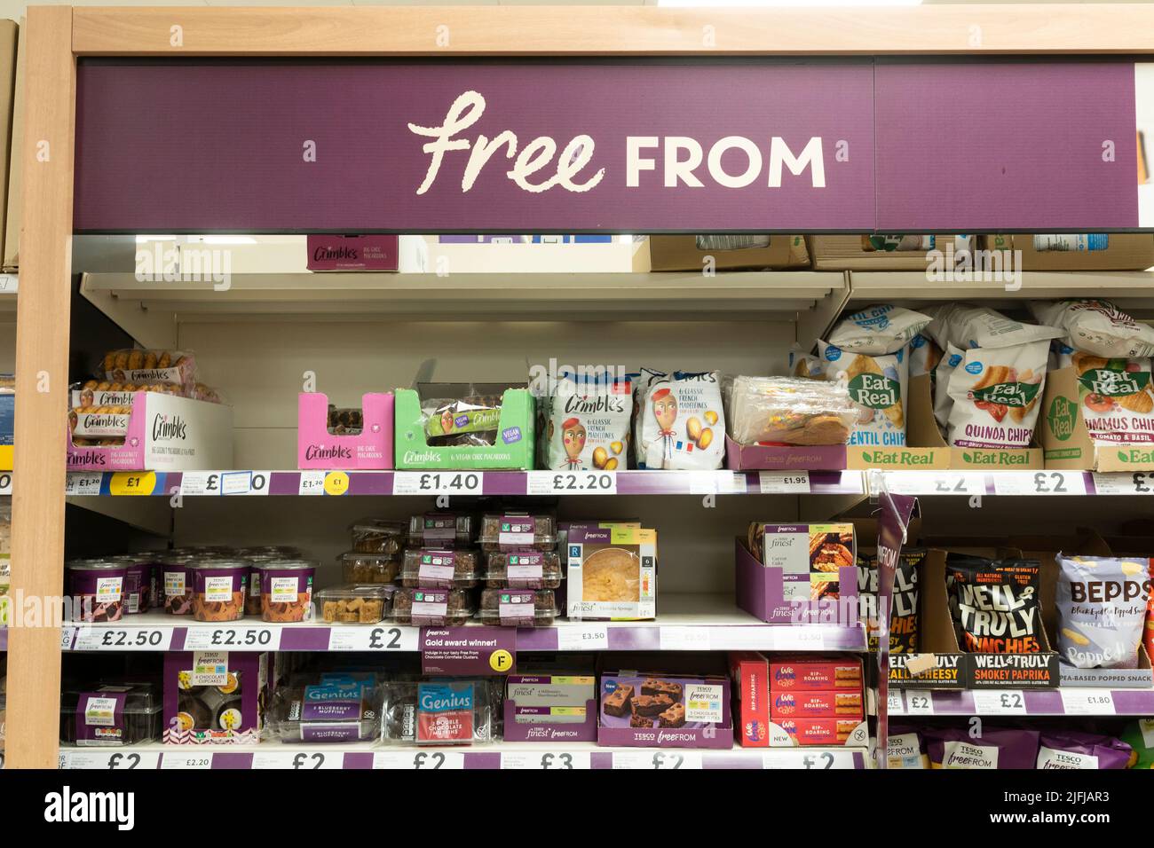 A gluten free aisle with gluten free products on shelves with a 'Free From' advertising board at a Tesco supermarket in Basingstoke, UK Stock Photo