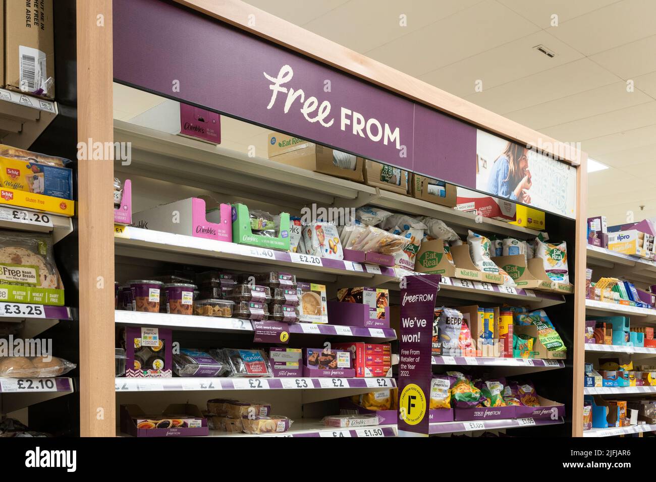 A gluten free aisle with gluten free products on shelves with a 'Free From' advertising board at a Tesco supermarket in Basingstoke, UK Stock Photo