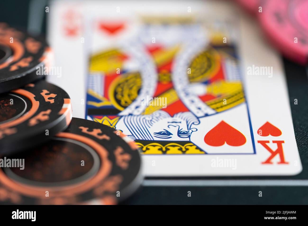 Closeup of a king of hearts playing card and poker betting chips on a poker mat. Concept - poker strategy, gambling, betting, gambling addiction Stock Photo