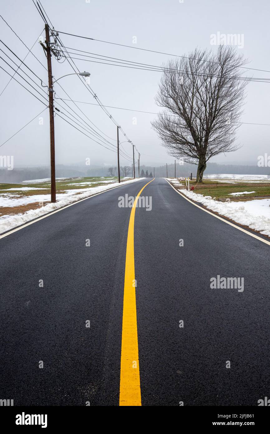A road with a bright yellow line running down the middle in Templeton, Massachusetts Stock Photo