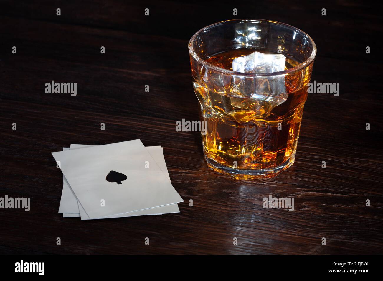 Old West Gambling. Playing cards and whiskey on wooden table Stock Photo
