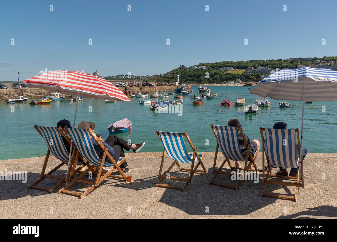St Ives, Cornwall, England, UK. 2022.  Holidaymakers relax in deck chairs on the harbourside looking towards Porthminster beach. St Ives famous holida Stock Photo