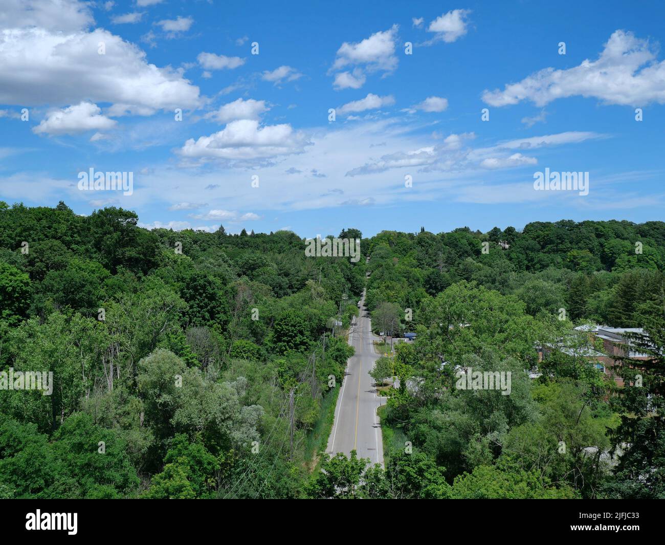 Looking down from a bridge onto a two lane valley road surrounded by trees Stock Photo