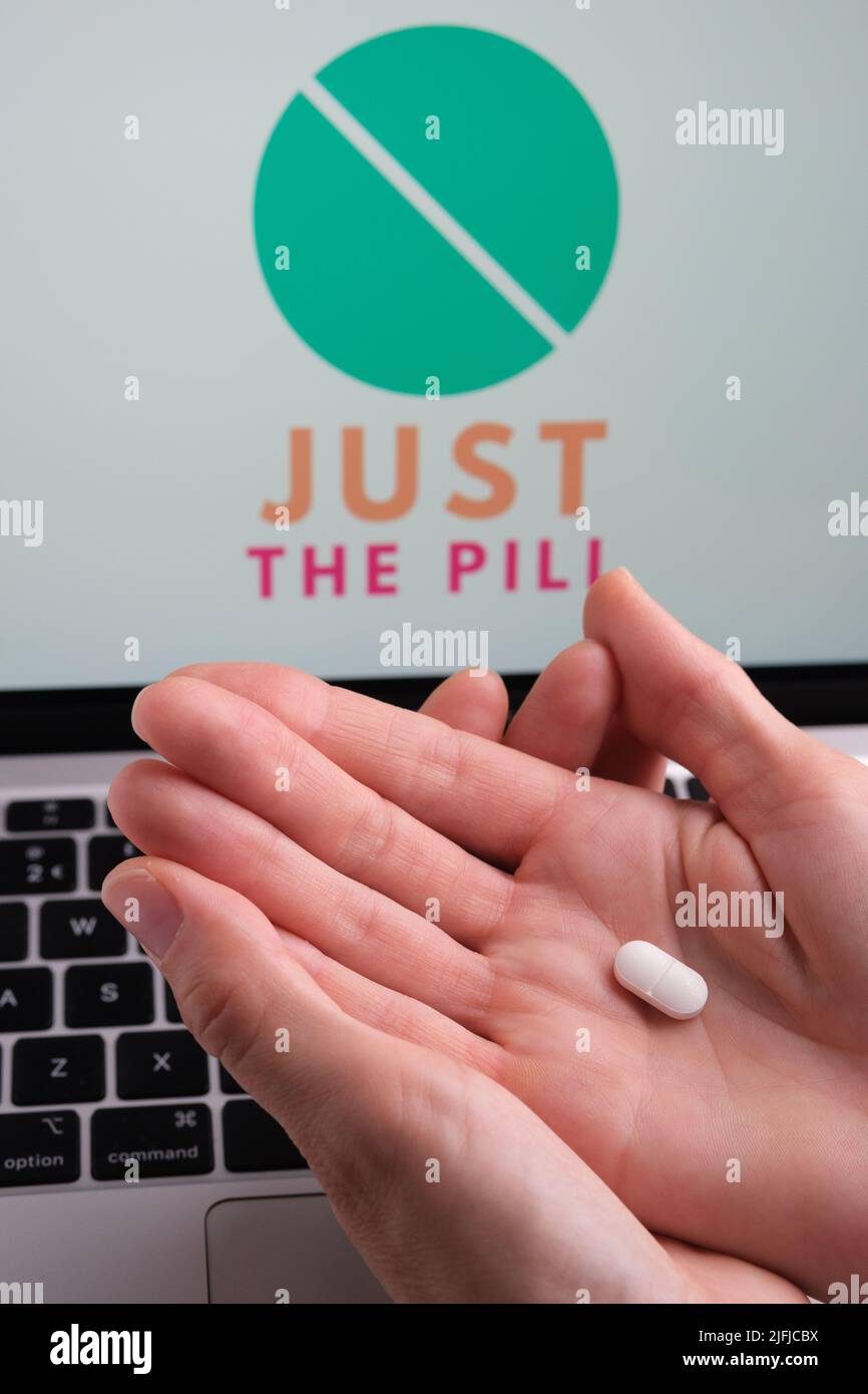 White pills and JUST THE PILL company logo on a blurred background. Concept for online telehealth abortion platform. Stafford, United Kingdom, July 3, Stock Photo
