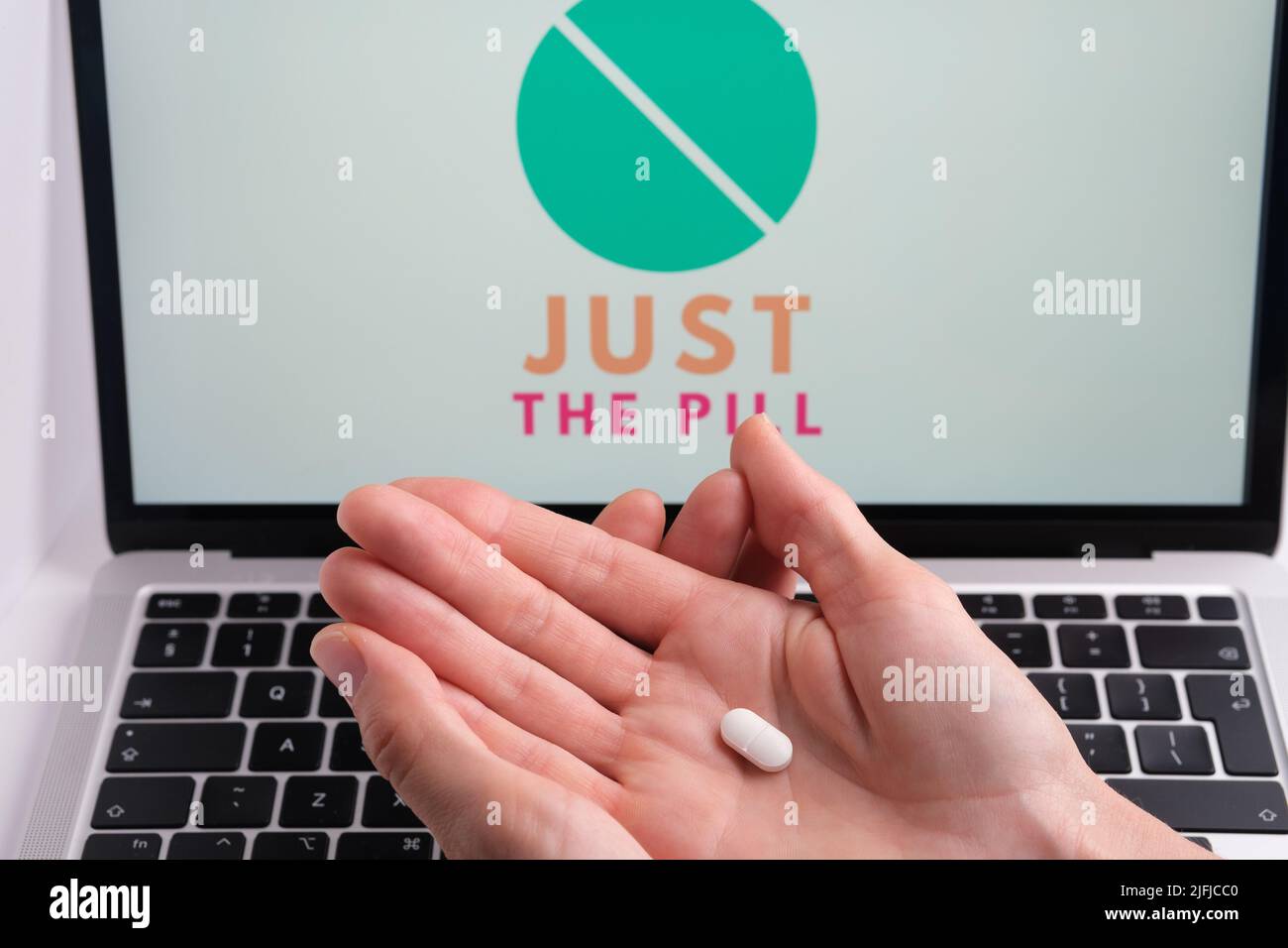 White pills and JUST THE PILL company logo on a blurred background. Concept for online telehealth abortion platform. Stafford, United Kingdom, July 3, Stock Photo