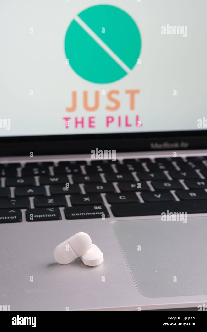 White pills and JUST THE PILL company logo on a blurred background. Concept for online telehealth abortion platform. Stafford, United Kingdom, July 3, Stock Photo