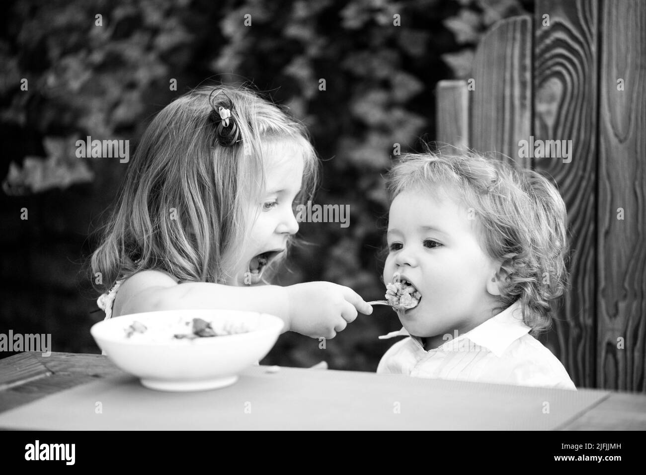 Little funny girl sister feeding baby. Cute funny babies eating, baby ...