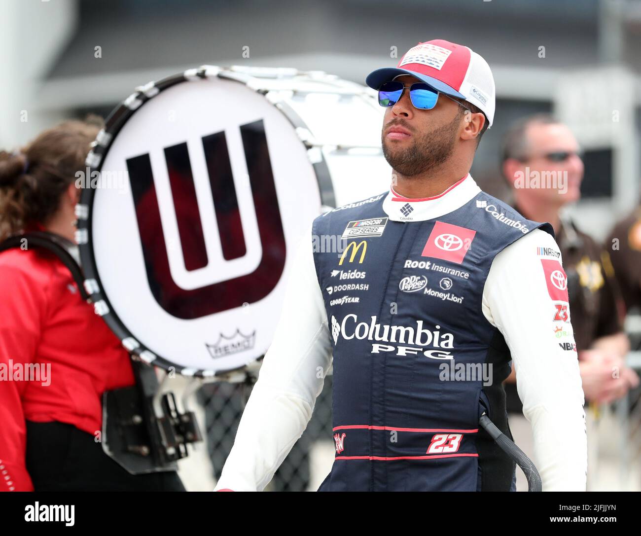 Plymouth, Wisconsin, USA. 3rd July, 2022. Bubba Wallace, driver of the #23 Columbia Sportswear Company Toyota, walks past the Wisconsin Badgers band before the NASCAR Cup Series Kwik Trip 250 at Road America on July 03, 2022 in Plymouth, Wisconsin. Ricky Bassman/Cal Sport Media/Alamy Live News Stock Photo