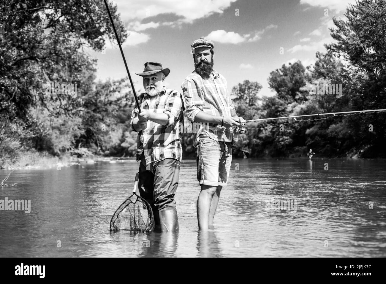 Fly fishing for trout. Father with son on the river enjoying fishing holding fishing rods Stock Photo