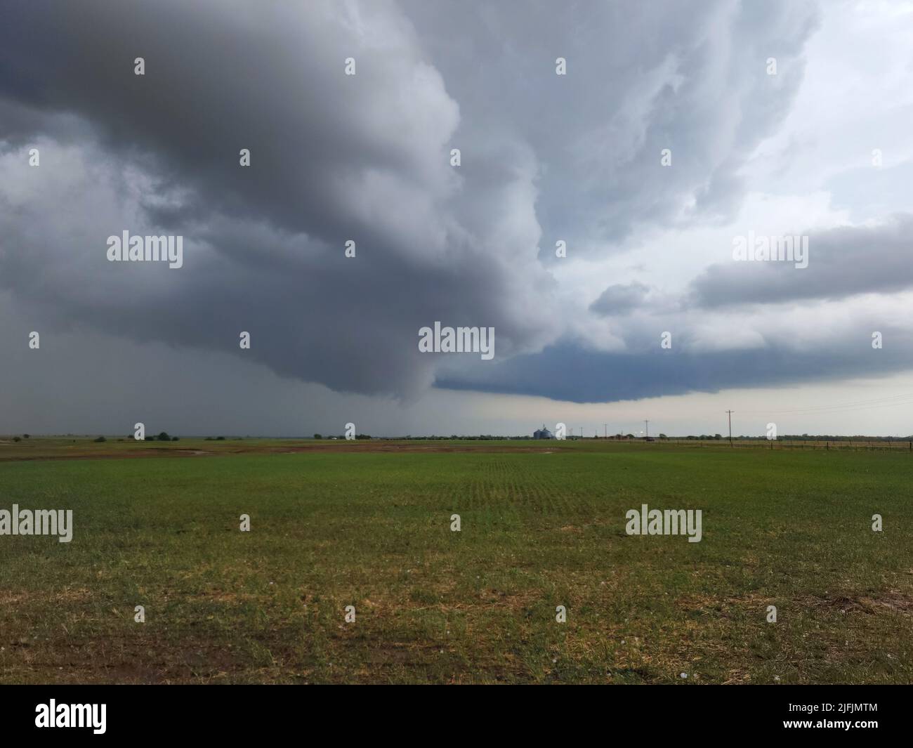 Storm clouds over an agricultural field in Oklahoma with hailstones in the foreground. Stock Photo