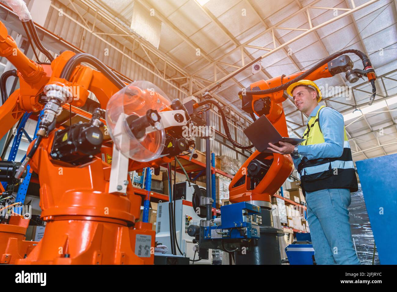 Worker man working with robot arm automate welding machine in modern metal factory. Engineer program robotic in heavy industry. Stock Photo