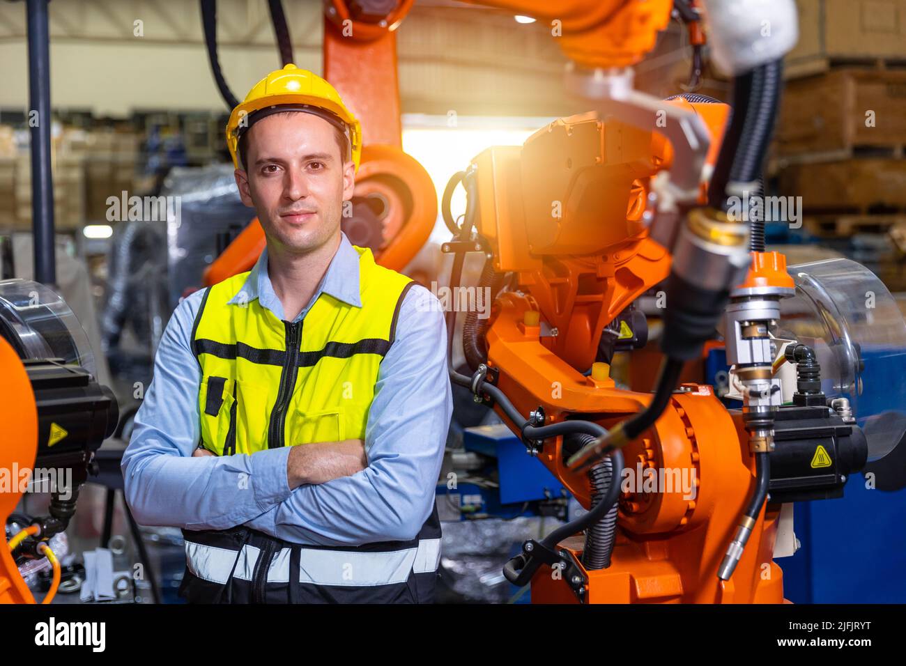 Portrait smart engineer man working with advance robotic machine weling in heavy industry. Stock Photo