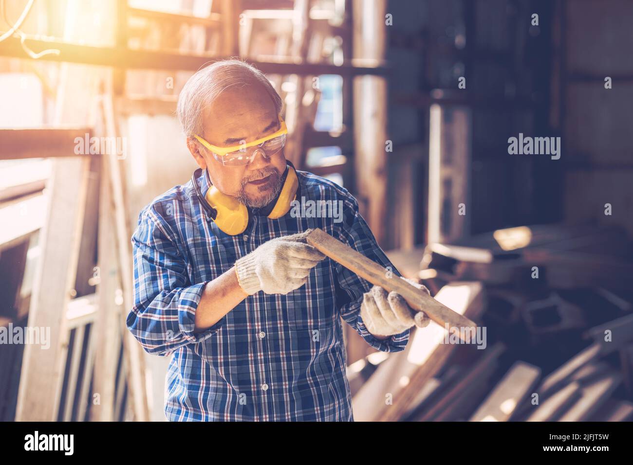 Senior Carpenter man Wood worker working hand made furniture in shop factory industry. male wooden craftsman builder working in workshop. Stock Photo