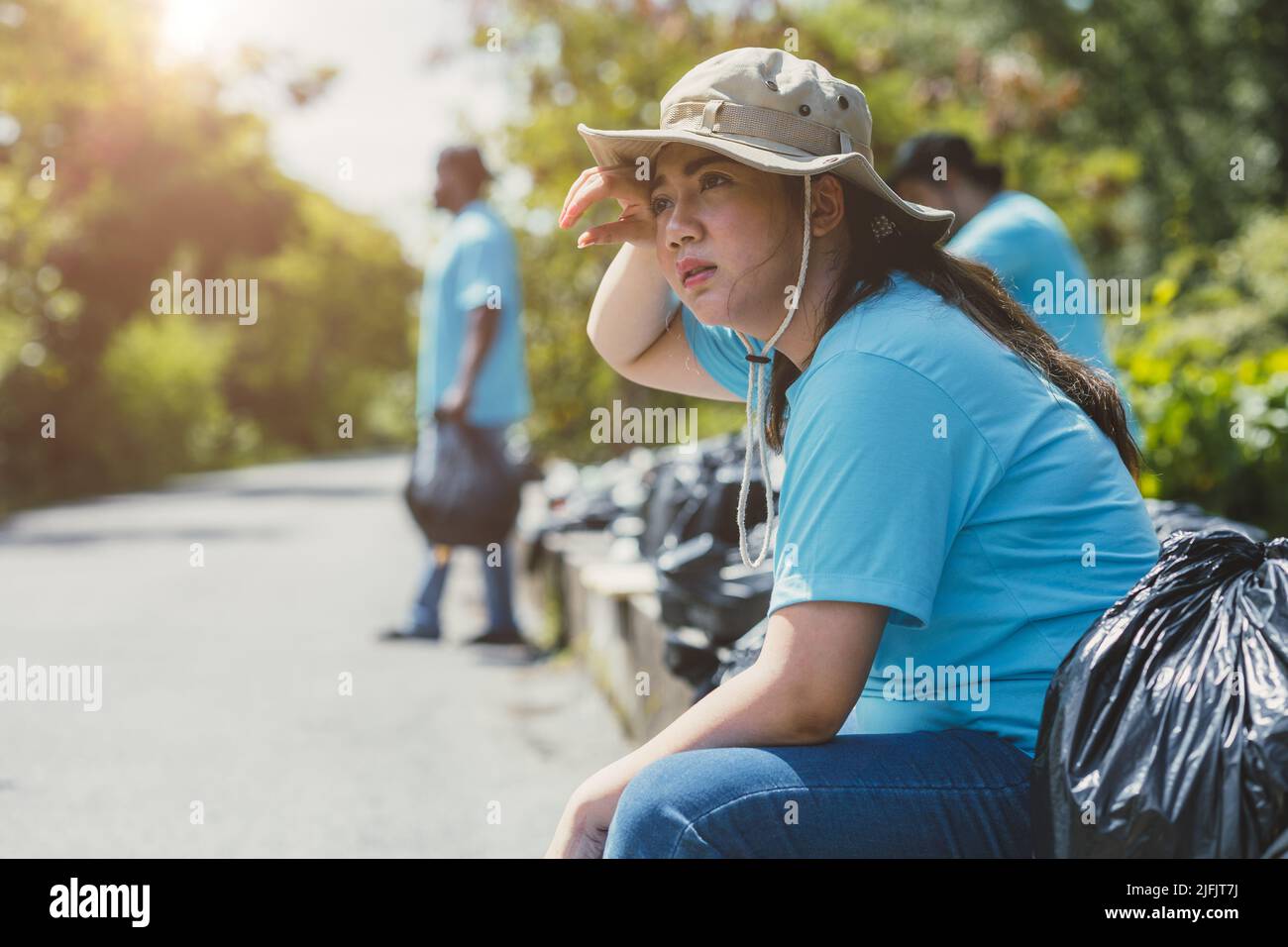 Tired exhausted volunteer people hard working cleaning garbage waste for help clean the world. Stock Photo