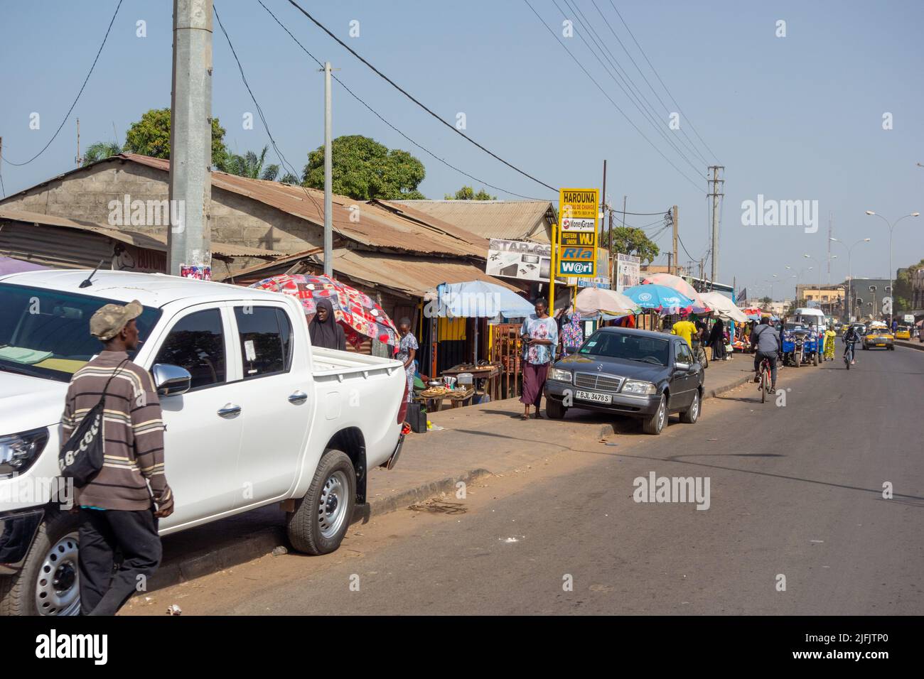 BAKAU, THE GAMBIA - FEBRUARY 6, 2022 parked cars on the  Old Cape Road Stock Photo